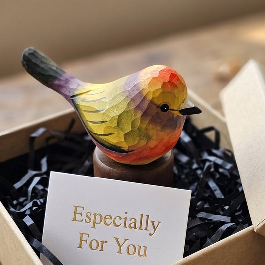 A small hand-painted bird figurine with a geometric, faceted pattern in yellow, orange, green, and purple, displayed in a kraft gift box with black shredded paper and a card that reads 'Especially For You'.