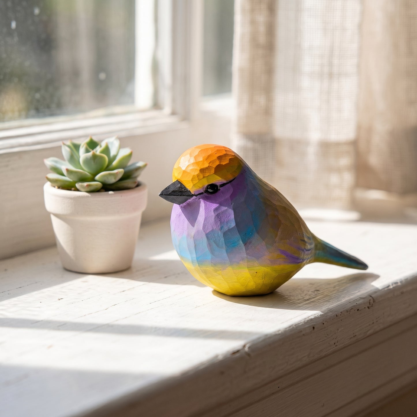 Hand-carved wooden White-browed Tit-warbler figurine resting on a stone windowsill next to a potted succulent in a bright sunlit room.