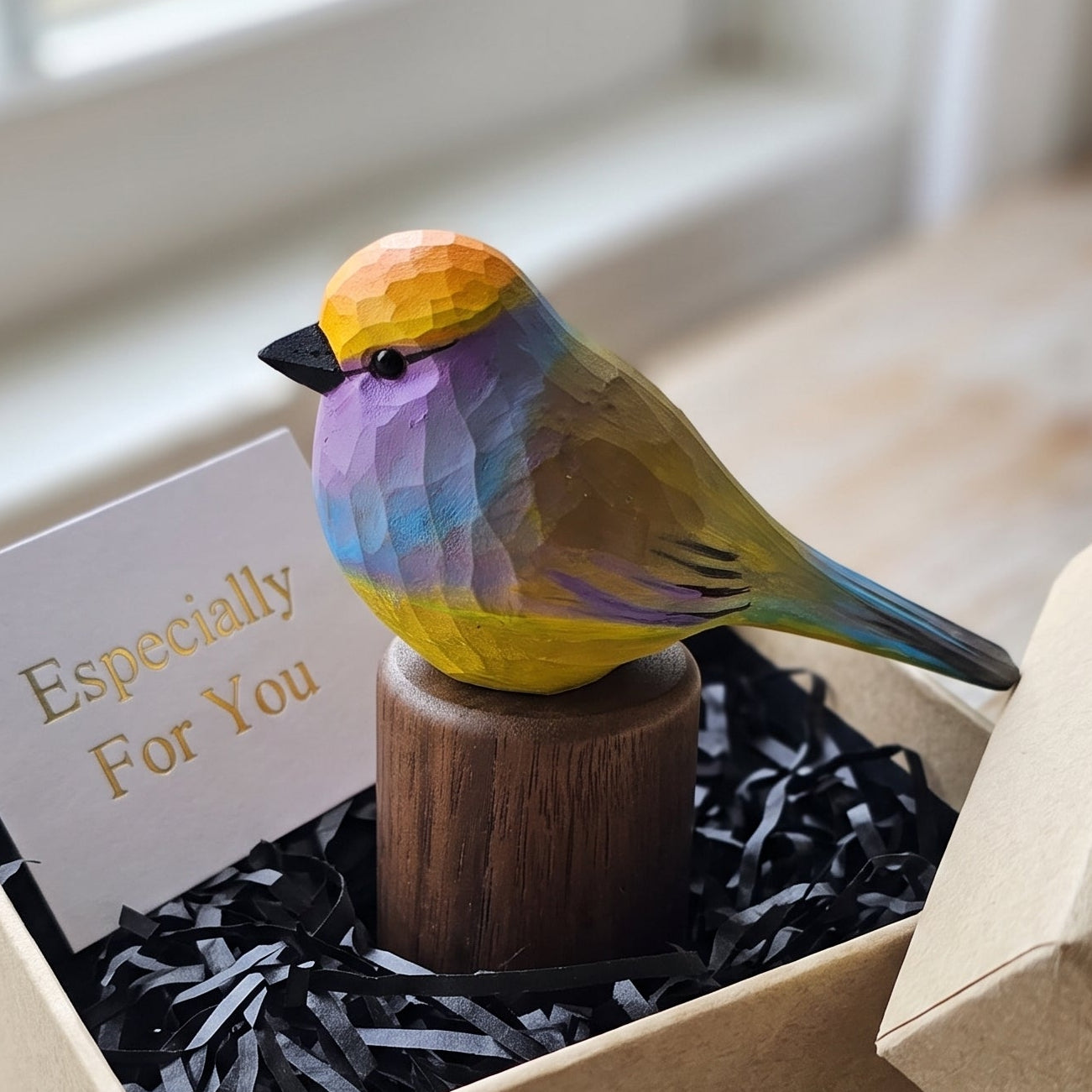 Hand-carved wooden White-browed Tit-warbler figurine on a black walnut base inside an open kraft gift box with black shredded paper and an "Especially For You" card.