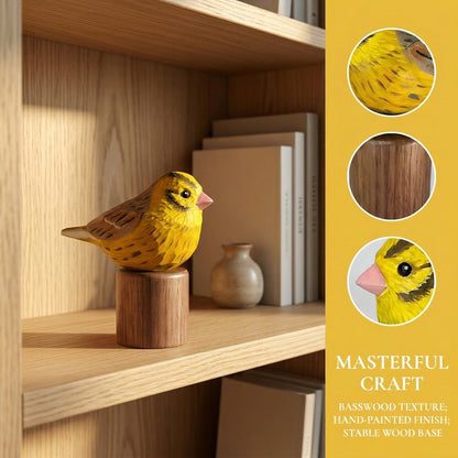 A handcrafted wooden Yellowhammer figurine in bright yellow and brown tones, displayed on a wooden bookshelf next to a small vase, with three circular detail insets and text highlighting the basswood texture and hand-painted finish.
