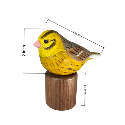 A hand-carved wooden Yellowhammer figurine with yellow, brown, and black painted details, mounted on a cylindrical wooden base. Measurement lines and text indicating 2 inch height, 4 inch length, and 1.